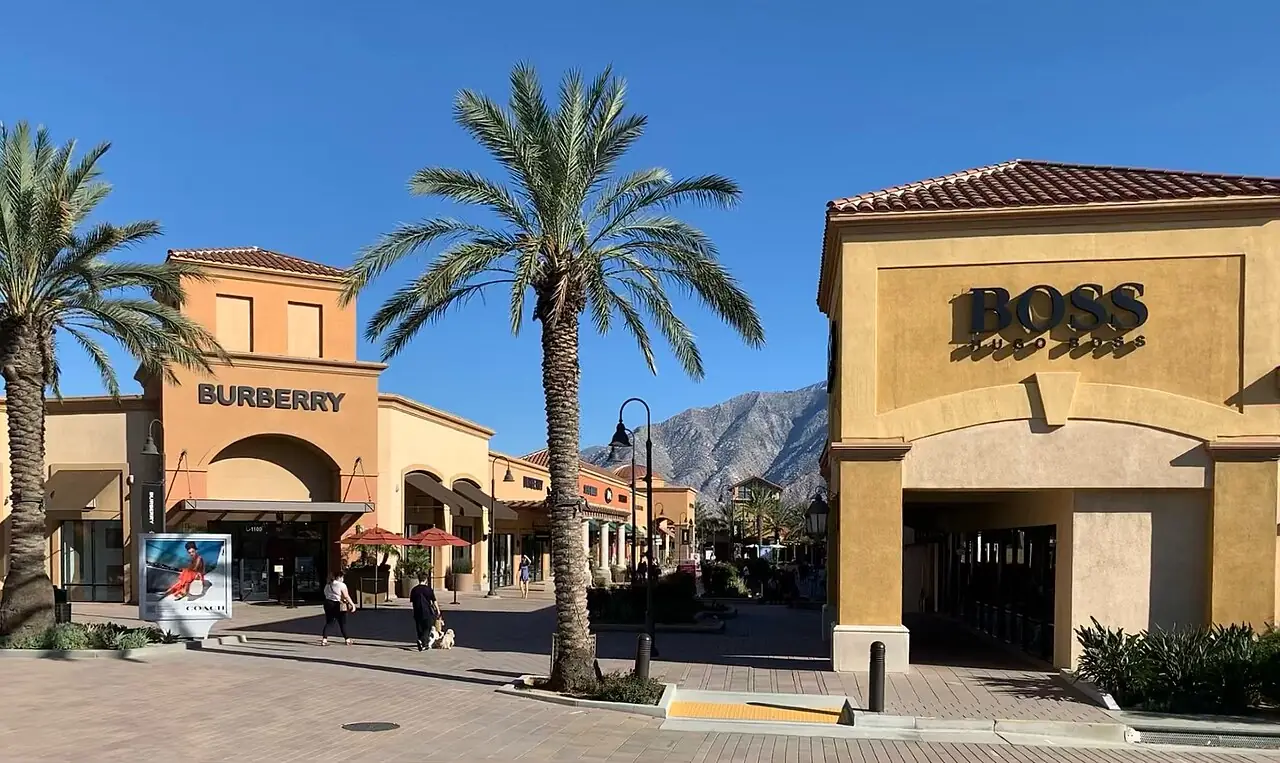 ヤシの木と山を背に、ブランドの店が並ぶアウトレットの通り